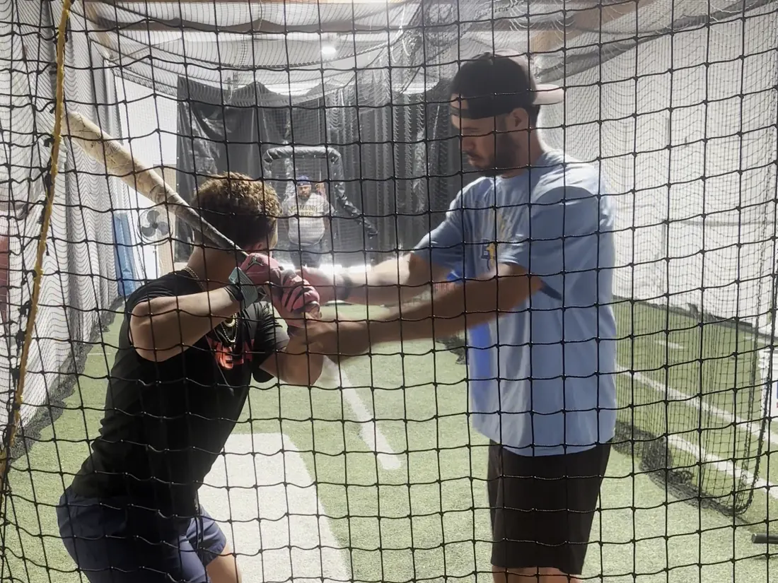 A coach guiding a hitter's hands inside The Lab