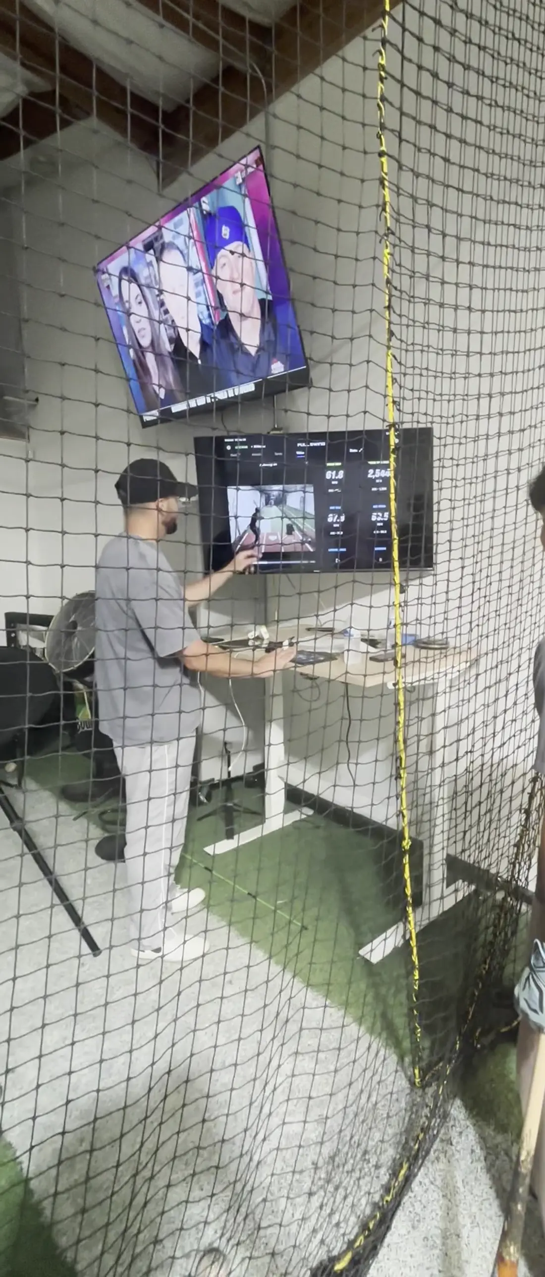 A coach reviewing a hitter's session on the screens at The Lab