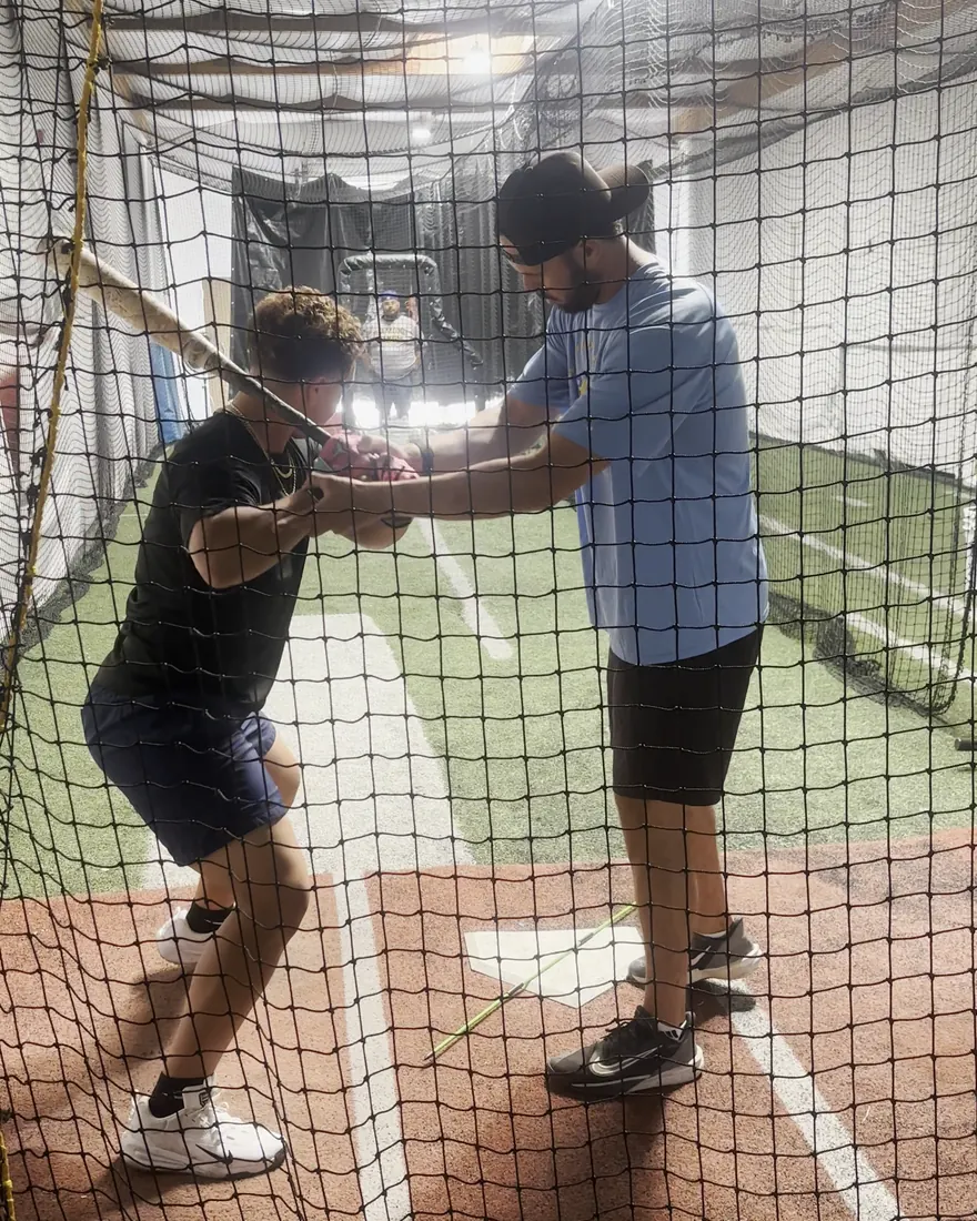 A coach working hands-on with a high school hitter at The Lab